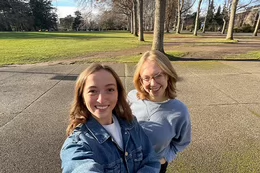 Two students in the quad outside with nearby trees
