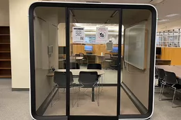 Tek booth with 4 chairs and a table with a white board.