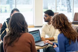 Four students sitting at a low table in front of a window