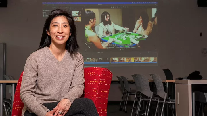 Angie sitting in a classroom with a projected video on the wall..