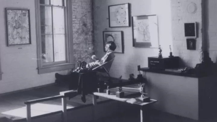 Black and white photo of a woman sitting in a chair staring out a window