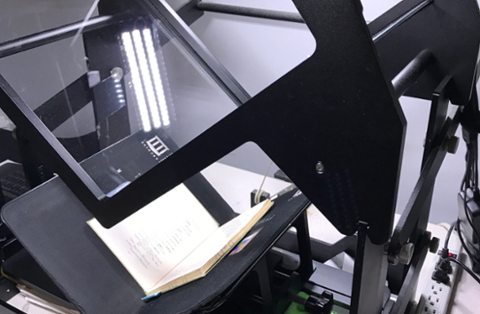 A large digital scanner in the process of scanning a book.