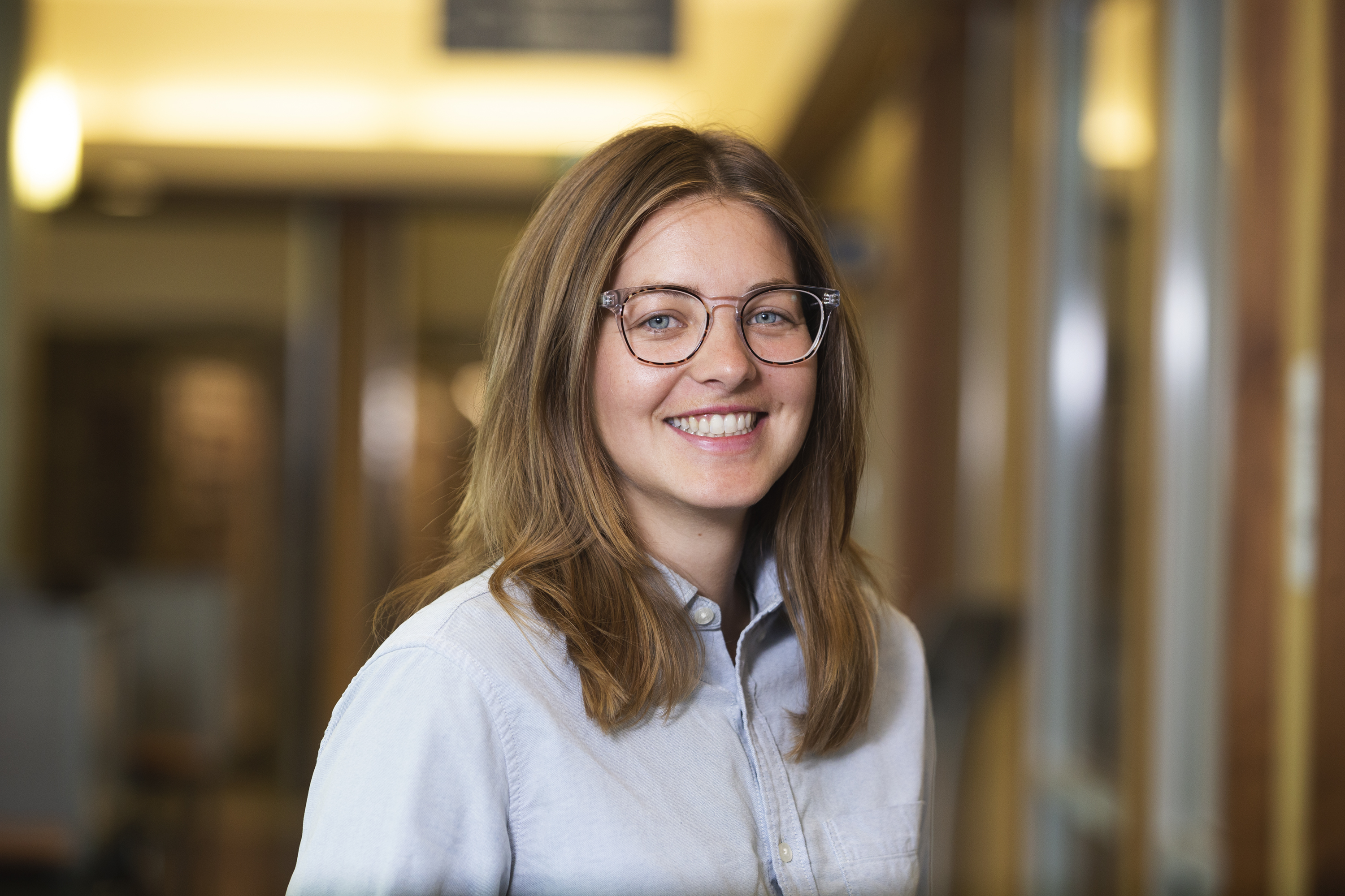 Head and shoulders photograph of a smiling woman with glasses and light brown shoulder length hair