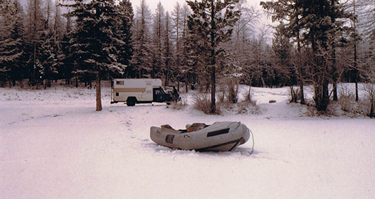 Inflatable zodiax on frozen lake with truck in background