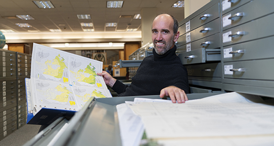 Tom sitting in front of maps pull-out drawer