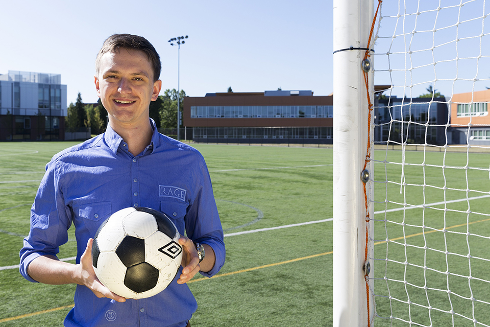 Mike Szymanski holding a soccer ball on a pitch