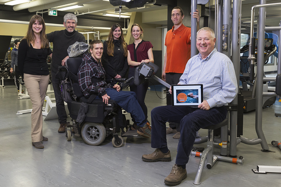 Group of researchers and subjects in a gym looking at the camera and smiling