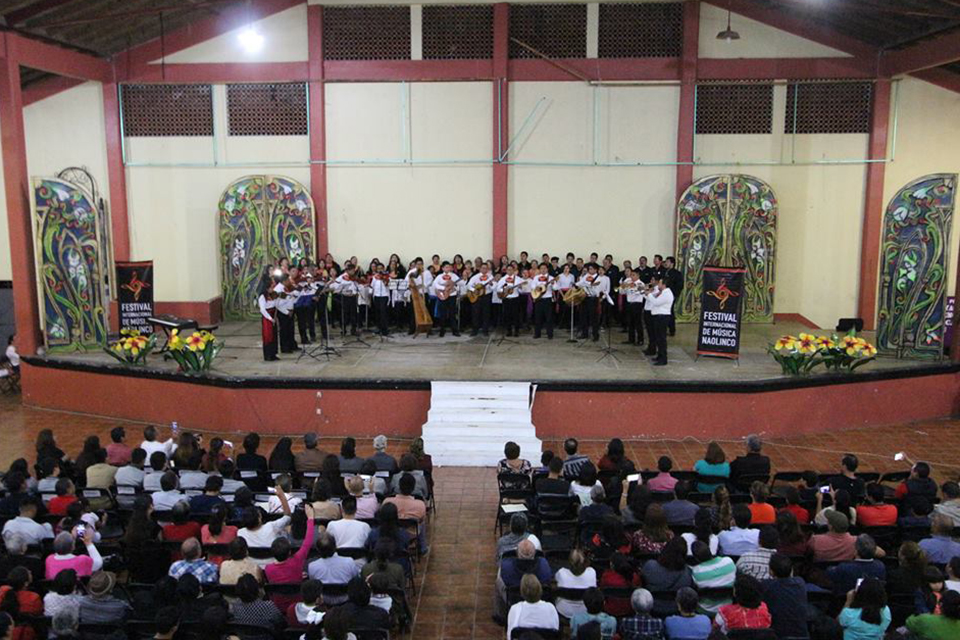 Musicians playing on a stage in Mexico with audience members watching
