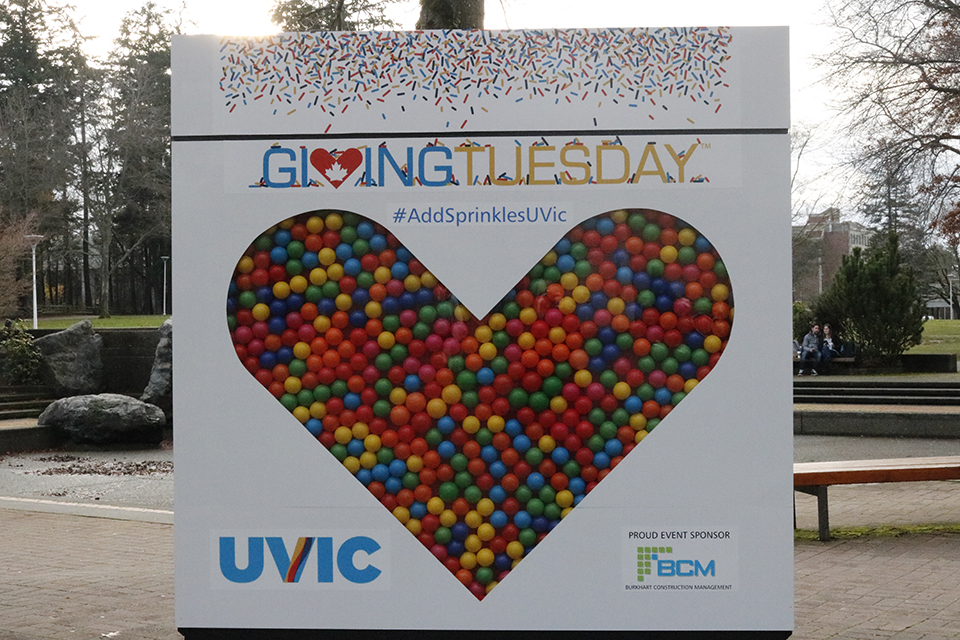 Large Giving Tuesday sign on campus with a colourful heart and sprinkles