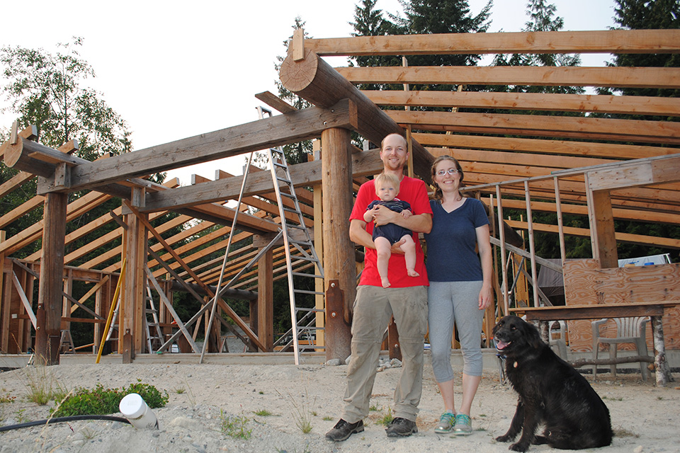 Cambria and William Logan with their baby and dog in front of their new home