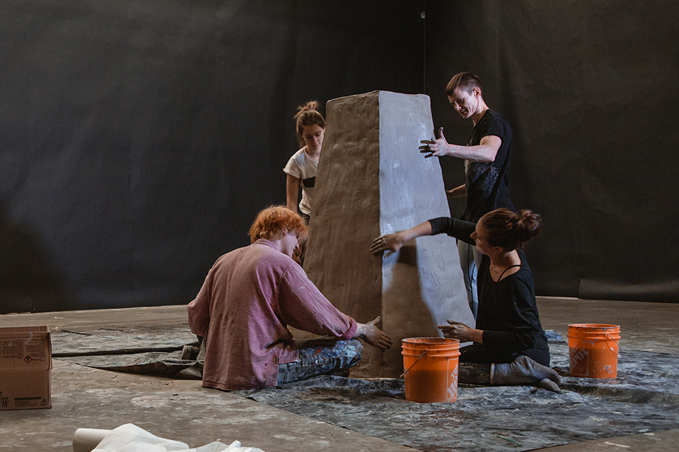Canadian-born transgender artist Cassils working on a raw clay block in an art studio