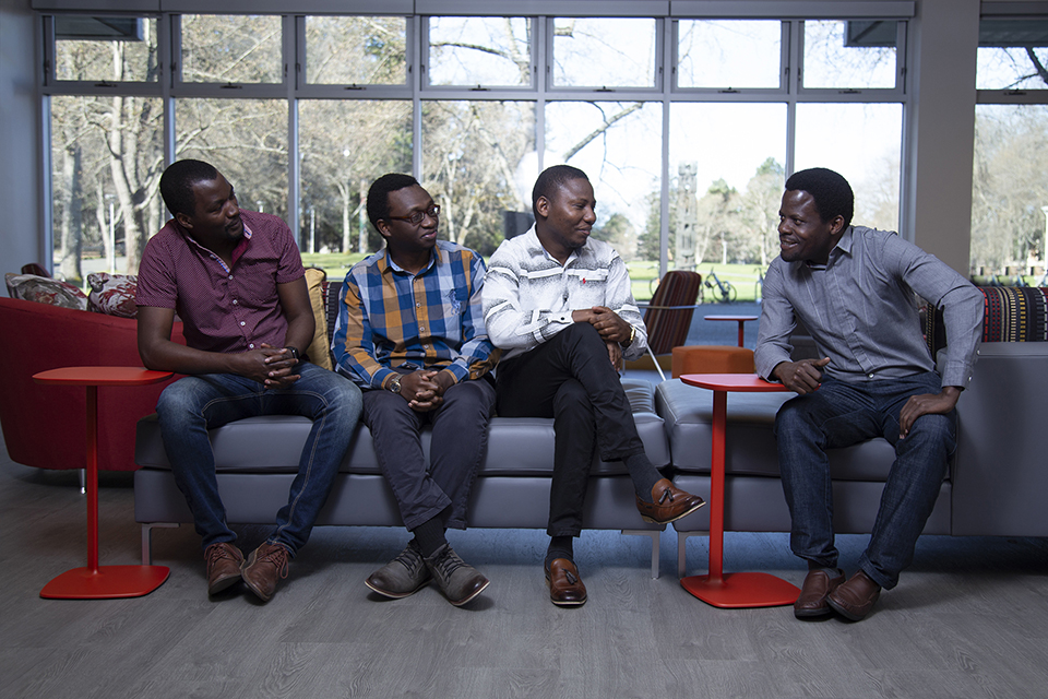 Four students sit at UVic and look into the camera