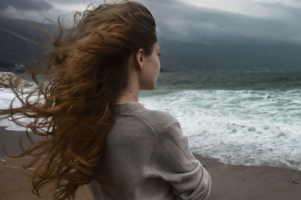 Woman on beach looking across a stormy sea