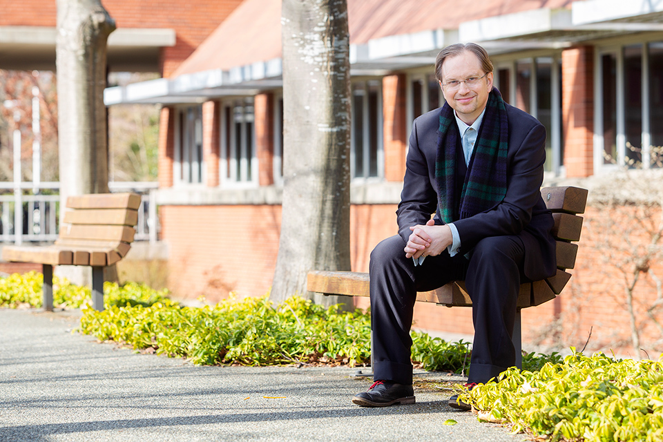 UVic business professor Brent Mainprize on a bench outside the Business and Economics Building