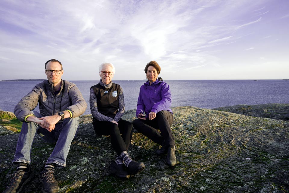 Researchers pose on a rock with the ocean in the background