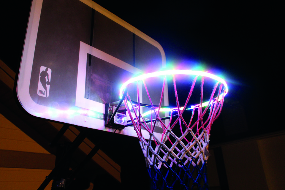 A basketball hoop lit up with a bright light around the ring.