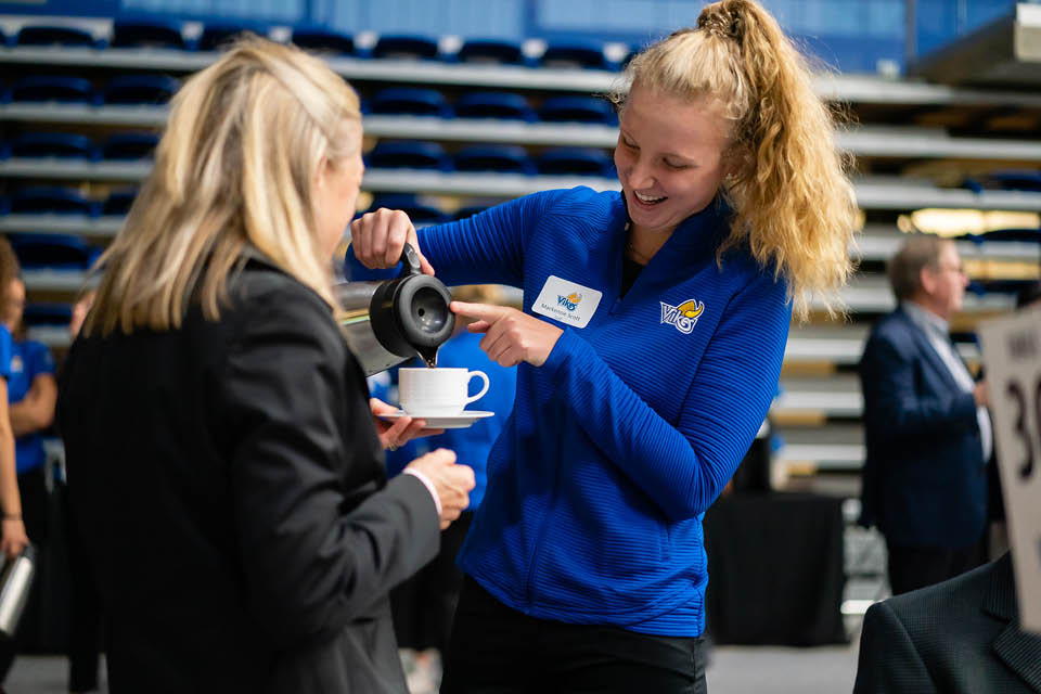 Student-athlete pours coffee for a guest.
