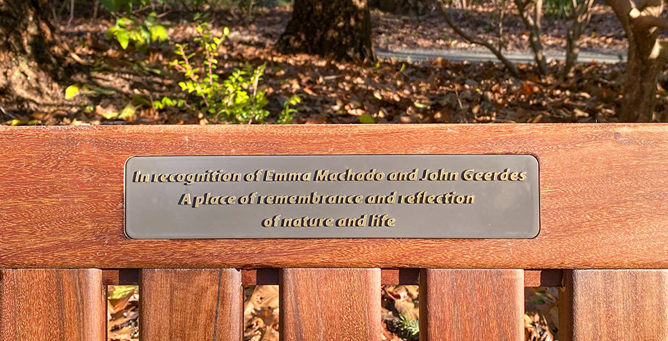 Closeup of memorial bench in Finnerty Gardens for Emma Machado and John Geerdes