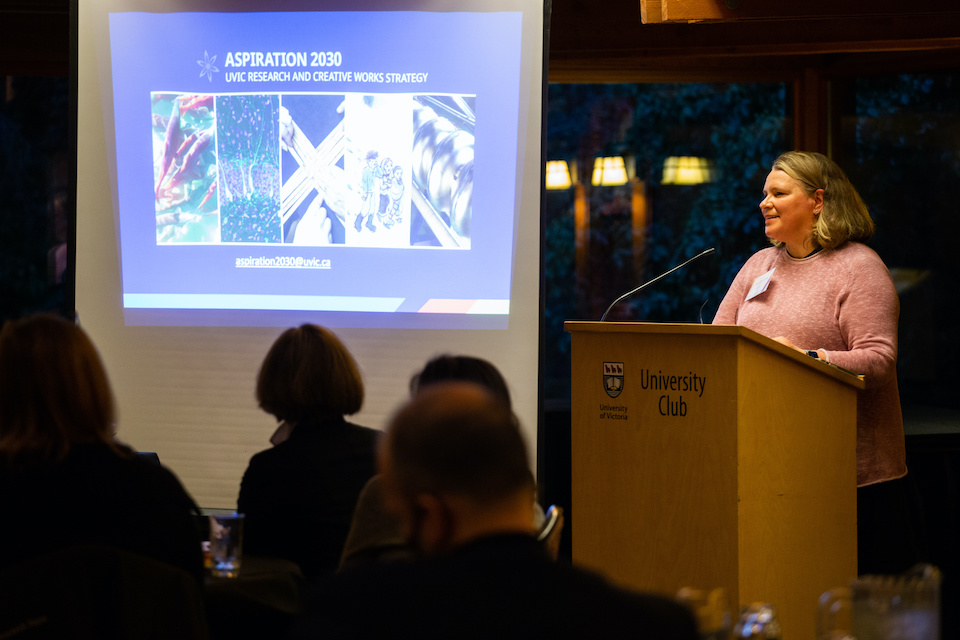 Lisa Kalynchuk is speaking at podium to UVic researchers.