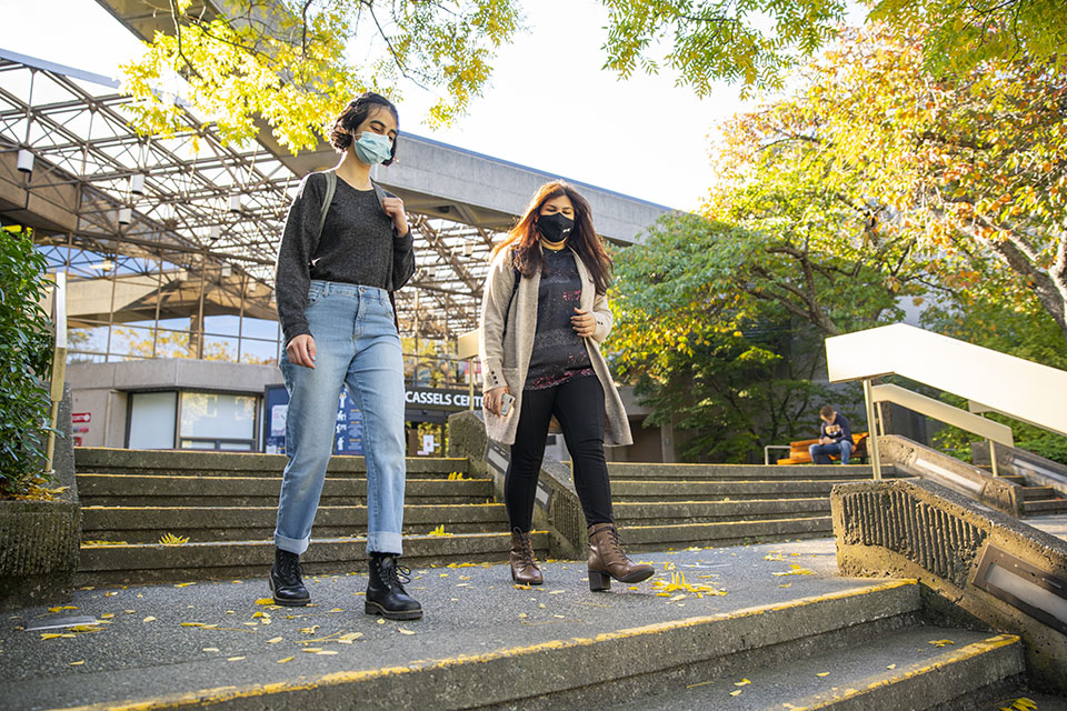 Two students wearing masks walk in front of the Jamie Cassels Centre.