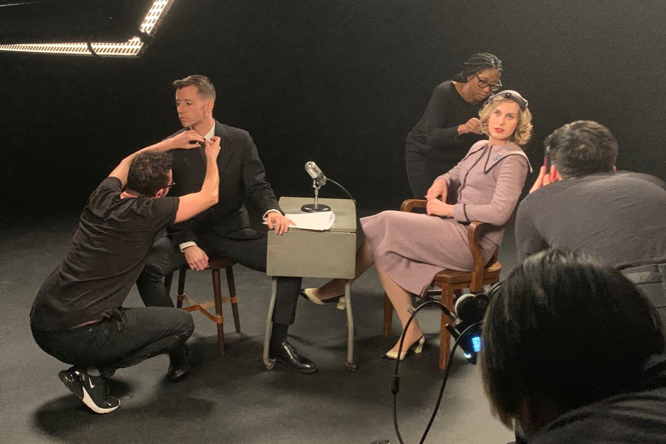Stage set of the new film Saving Agnes by UVic prof Chase Joynt showing two people on the propped stage of a talk show with three production team members getting them prepped for filming. (Credit: Donald Scherschligt)