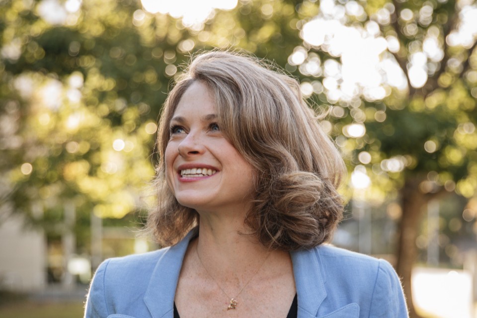 Researcher Madeleine McPherson stands outdoors on UVic’s campus, with trees and buildings in the background.