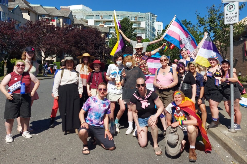 A group of people on the street, holding transgender and non-binary flags.