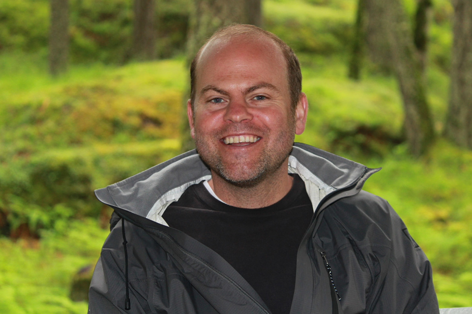 Close-up of UVic anthropologist Daromir Rudnyckyj in front of a forest
