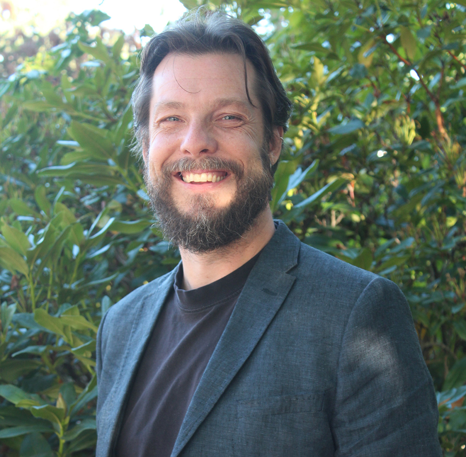 Portrait of Oliver Brandes of POLIS Project, against leafy campus backdrop