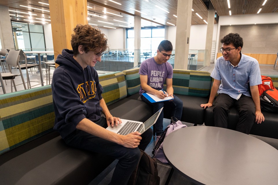 Three students sitting in new campus facilities.