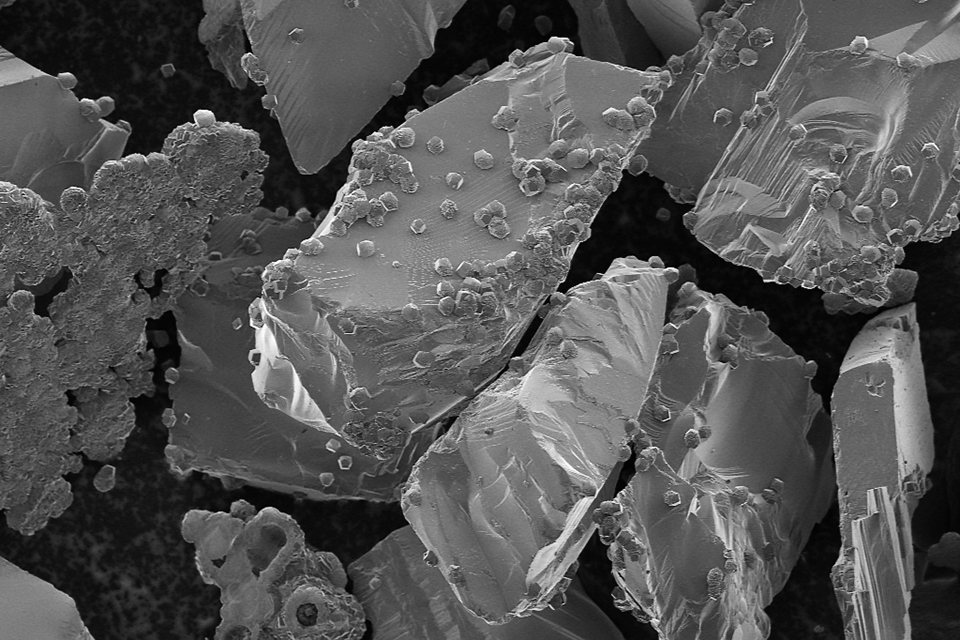 Solid carbonate mineral formation (small bumps) on basaltic minerals (large chunks), photographed through scanning electron microscopy. Credit: The Reactive Transport Group at the University of Calgary.