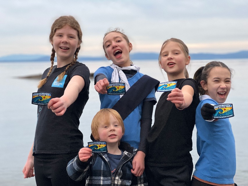 five girls standing and showing their badges