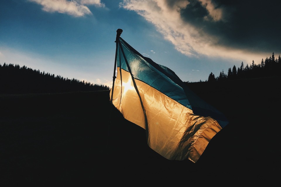 Flag of Ukraine against dark forest backdrop, reflecting protest against invasion