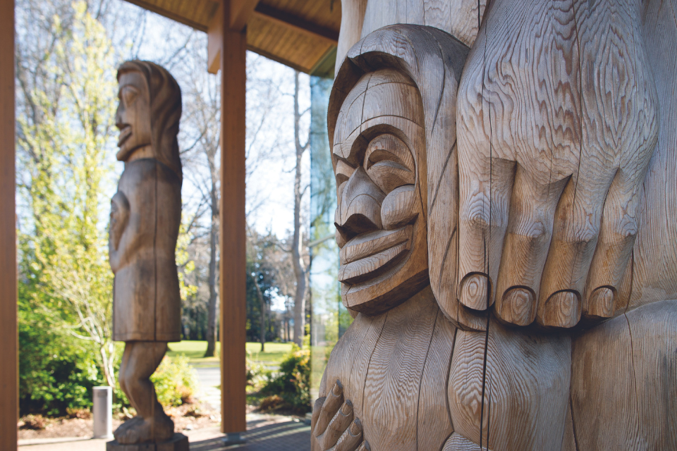 Welcome figures outside First Peoples House carved by Doug Lafortune (Tsawout)