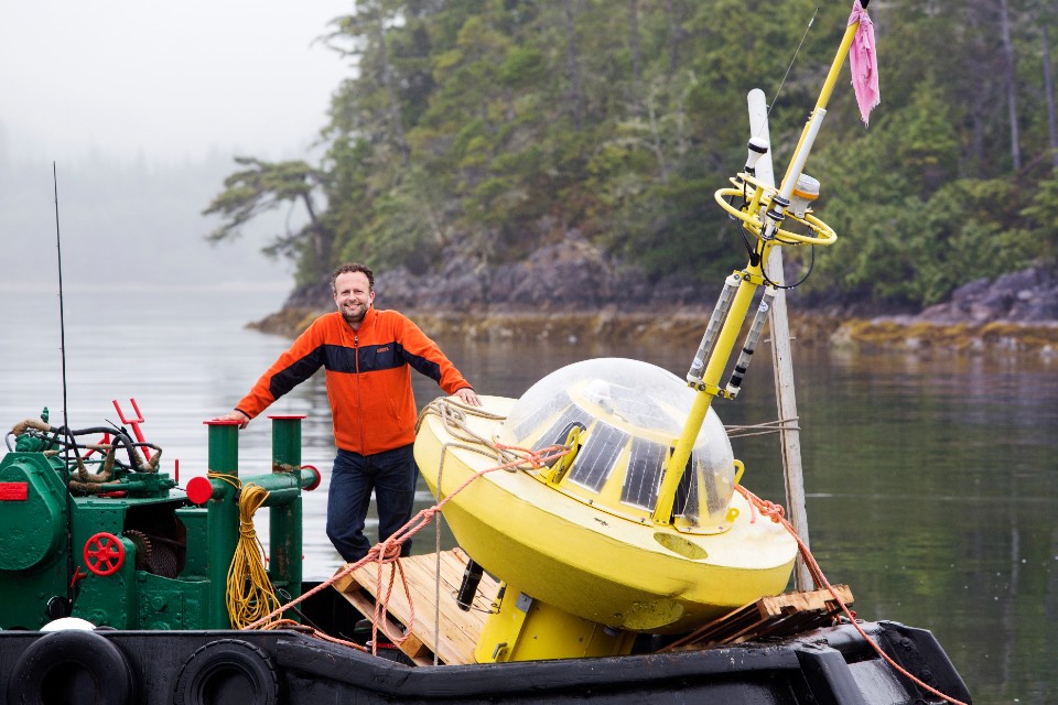 Brad Buckham, Chair, Mechanical Engineering & Co-Director, PRIMED, on the deck of the tugboat Service IX in Hot Spring Cove near Ucluelet, showcasing a similar type of buoy-based tidal data collection platform that will be deployed in the waters off Yuquot.