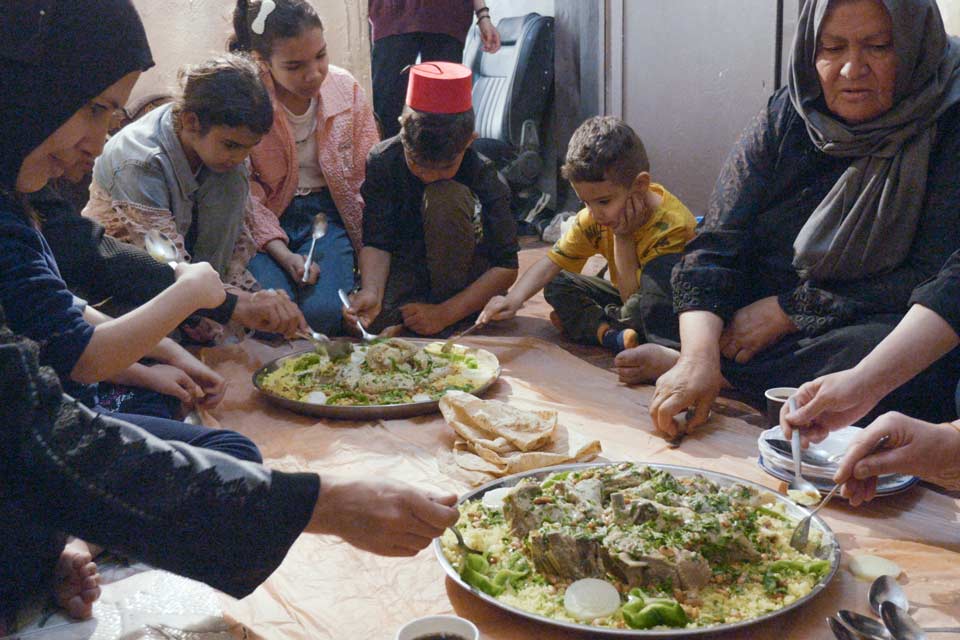 The Azzam family shares an iftar meal prepared by Aisha for Eid al-Fitr, marking the end of Ramadan.