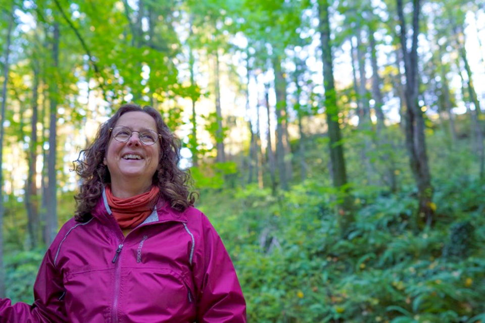 Environmental studies professor Kara Shaw standing on a forest slope.