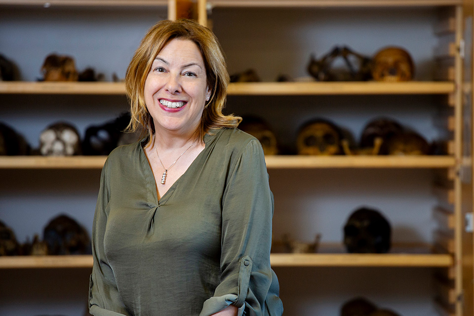 University of⁢ Victoria paleoanthropologist April ⁤nowell ‌sits in a lab with bones ⁢seen behind her.