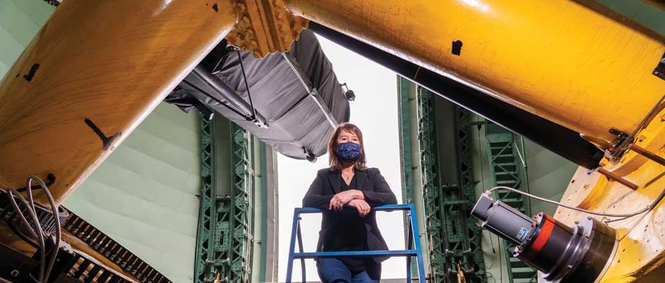 Kim Venn stands underneath a telescope at the Dominion Astrophysical Observatory