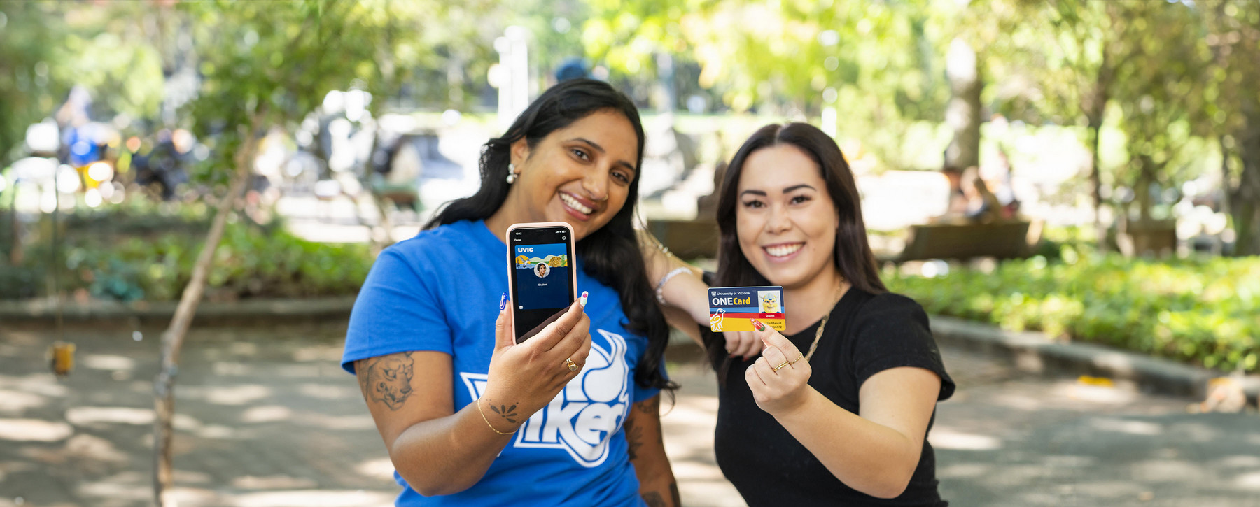 two women holding up physical card and mobile credentials