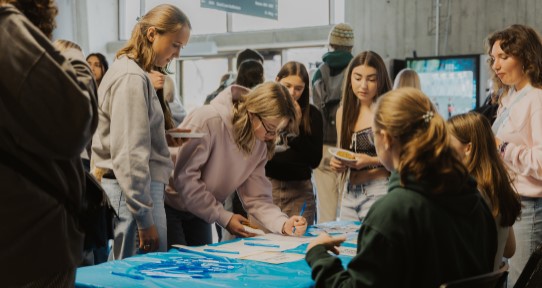 Students writing their name on name tags at check in for orientation.