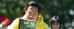 Student holding up a printed version of the New Student Handbook