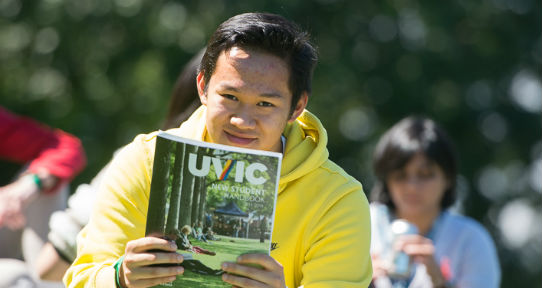 Student holding up a printed version of the New Student Handbook