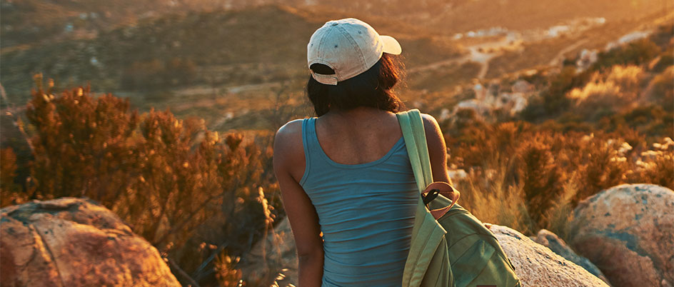 A woman sitting on a hilltop looking out over the landscape below