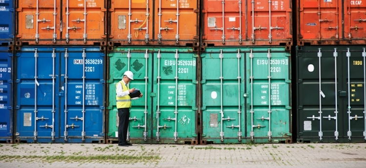 a man walking past a stack of cargo containers