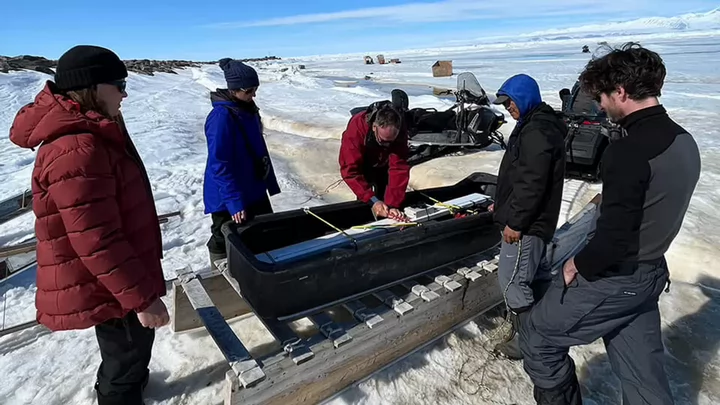 Mara Neudert (AWI Germany), Constanza Salvo (INRS Quebec), Trevor Bell (SmartICE), Andrew Arreak (SmartICE), and Grant Macdonald (UVic) load an electromagnetic ice profiler into the qamutik.