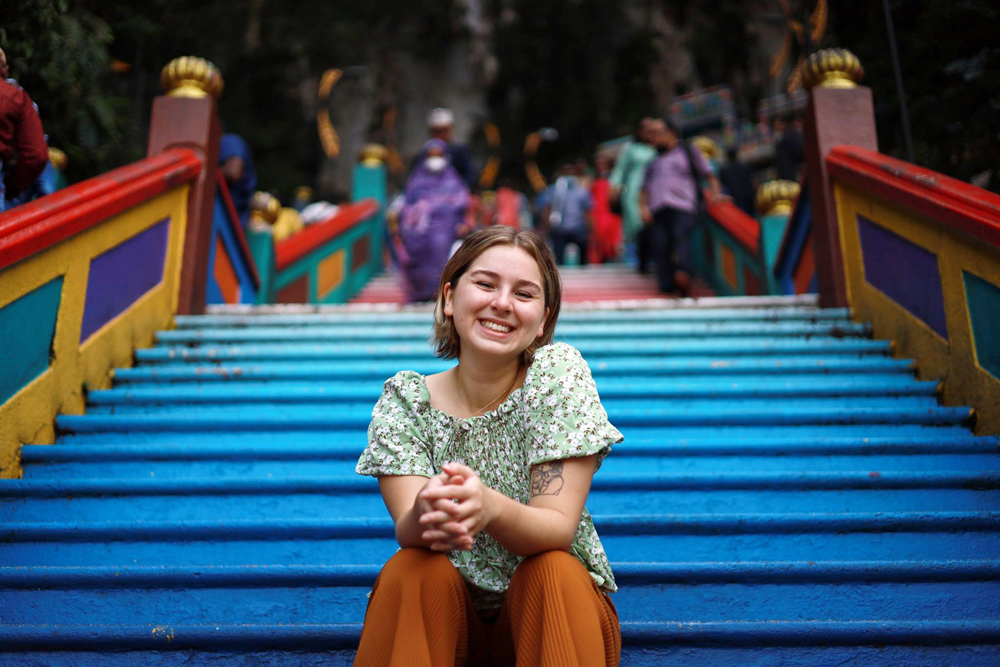 2022 CAPI intern Elly Thompson on the coloured steps of the Batu Caves temple near Kuala Lumpur
