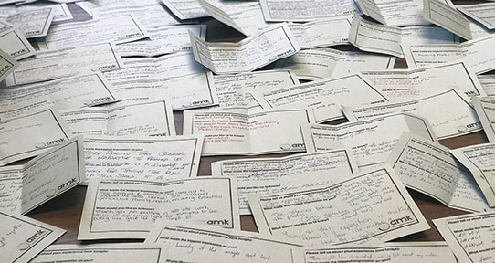 A photo of dozens of rectangular hand-written comment cards on a table.