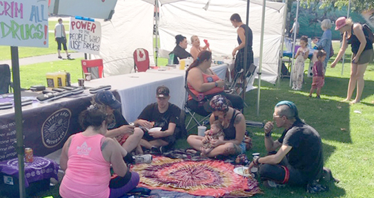 A photo of several people sitting on a blanket outside