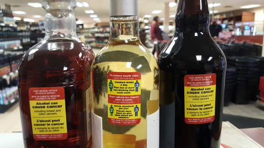 photo of CISUR's new alcohol warning labels affixed to bottles in the Whitehorse liquor store